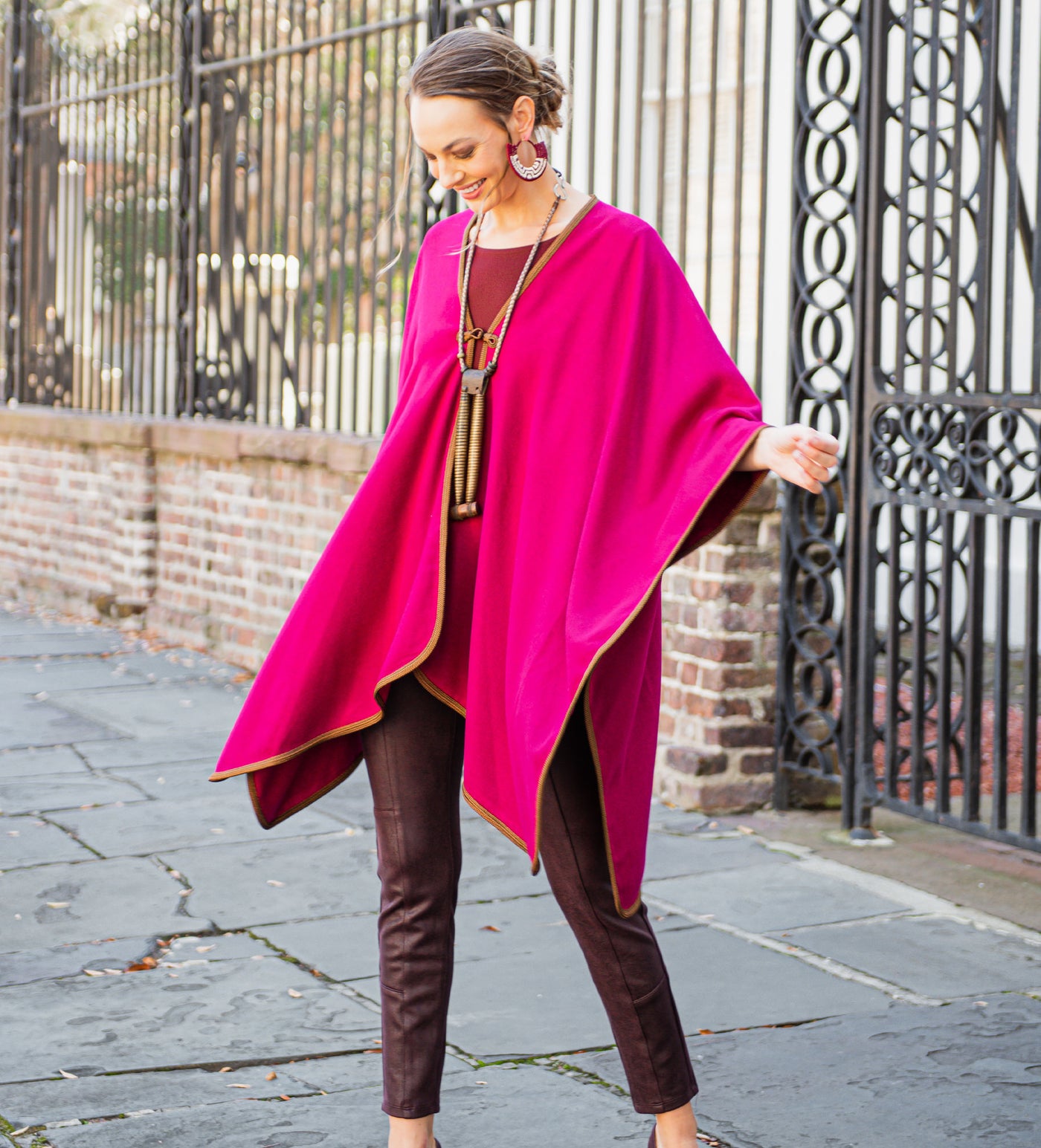 Woman in a deep fuchsia cape, dancing in the wind, over top deep burgundy accents.